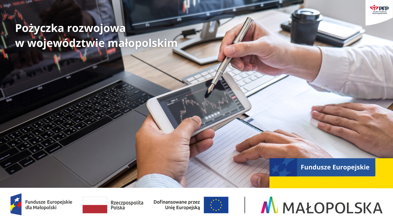 Dwie osoby pracują przy biurku: jedna trzyma tablet z wykresem finansowym i wskazuje go długopisem, druga robi notatki; w tle laptop i monitor z wykresami. Tekst: „Pożyczka rozwojowa w województwie małopolskim”. Na dole pasek logotypów: Fundusze Europejskie dla Małopolski, Rzeczpospolita Polska, Dofinansowane przez Unię Europejską, Unia Europejska, Małopolska; w prawym górnym rogu logotyp Polskiej Fundacji Przedsiębiorczości.